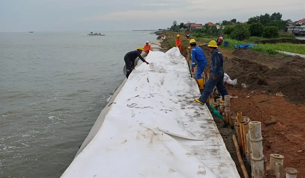 Proses pemasangan geotextile tube di bibir pantai untuk menangkal abrasi