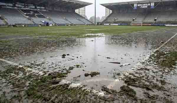 Lapangan sepak bola yang tergenang air dan rumput yang rusak karena lumpur